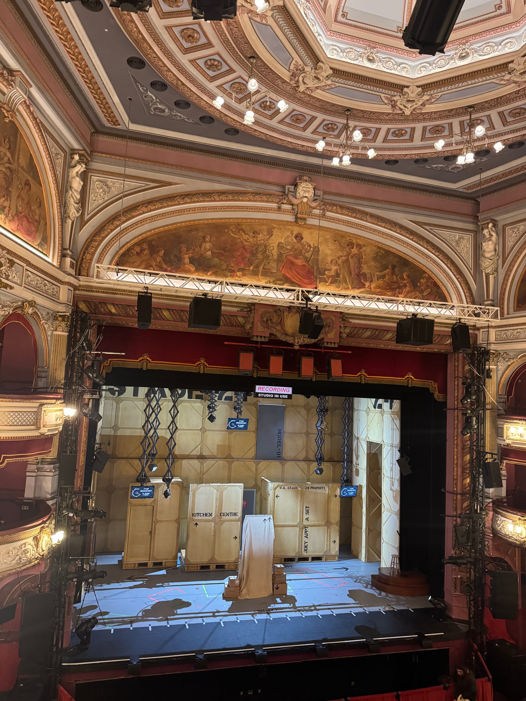 Wide view of the stage at the Alhambra Theatre in Bradford, showing the FRIENDS! The Musical Parody set designed as a TV studio, framed by the theatre’s decorative ceiling, balconies, and lighting rig.
