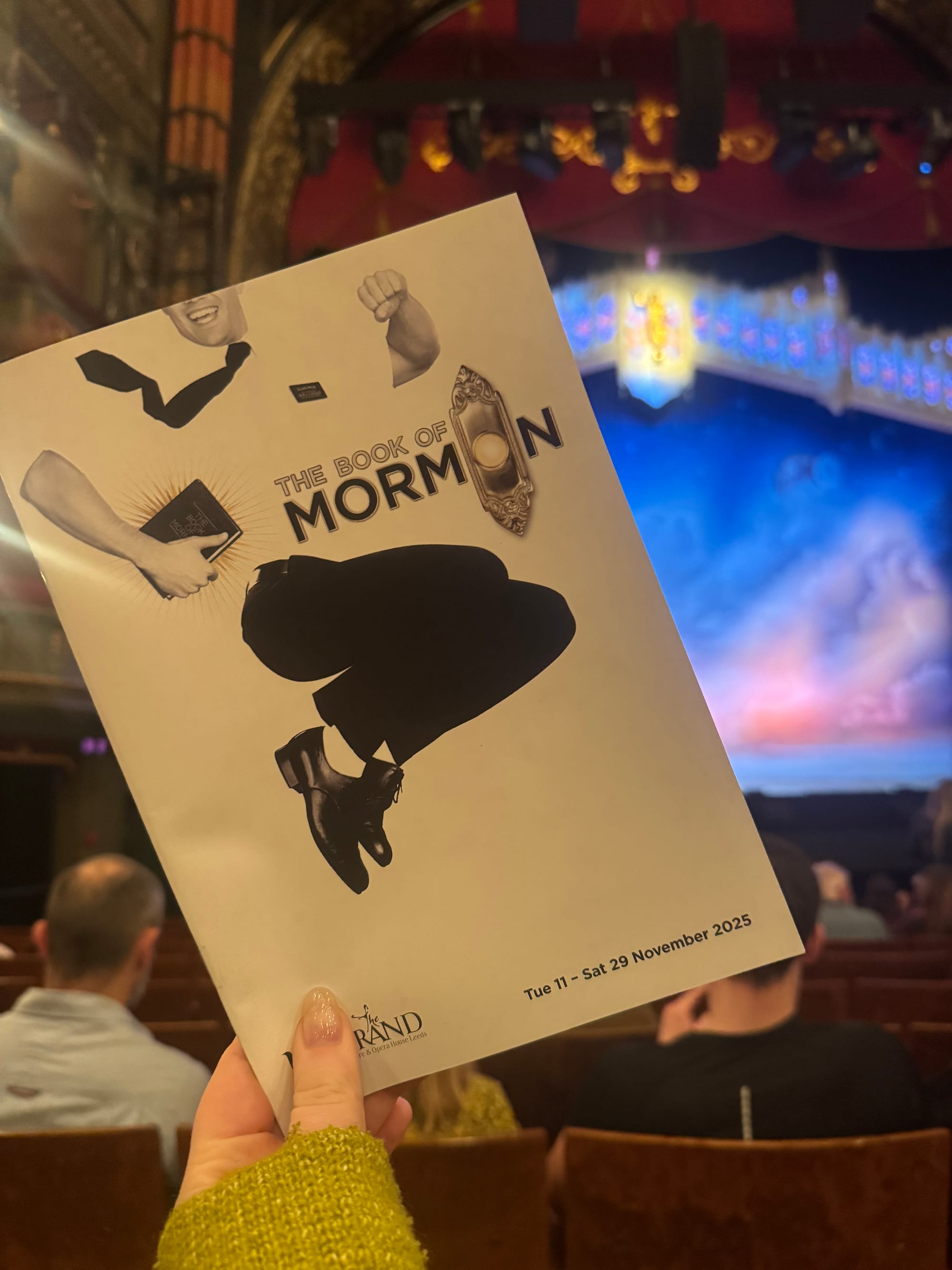 Playbill of "The Book of Mormon" held in a theater with ornate details and stage lit in blue. Date: Tue 11 - Sat 29 November 2025.
