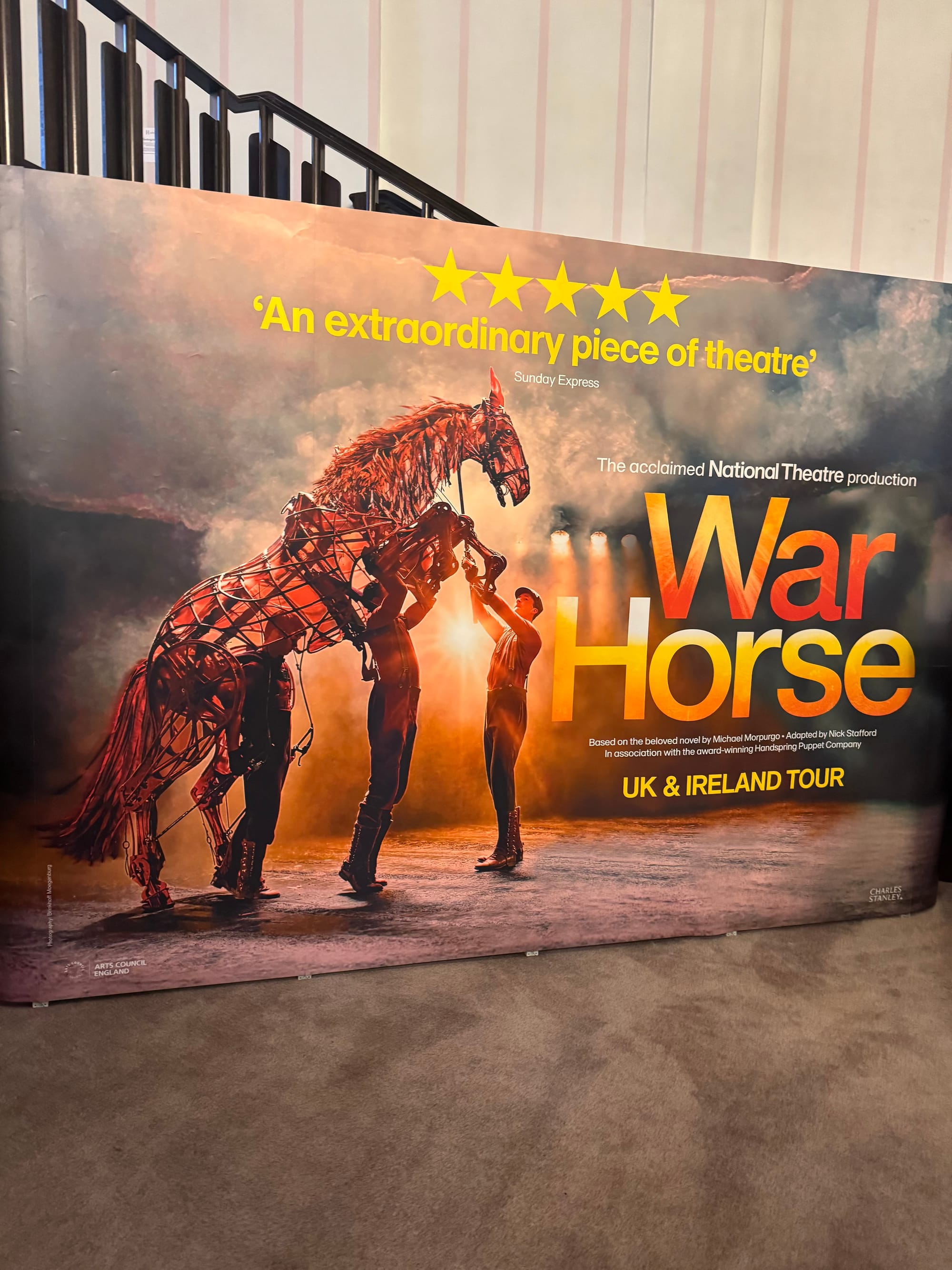 Banner for "War Horse" UK & Ireland tour. Features horse puppet with three handlers, glowing lights, and text: "An extraordinary piece of theatre."