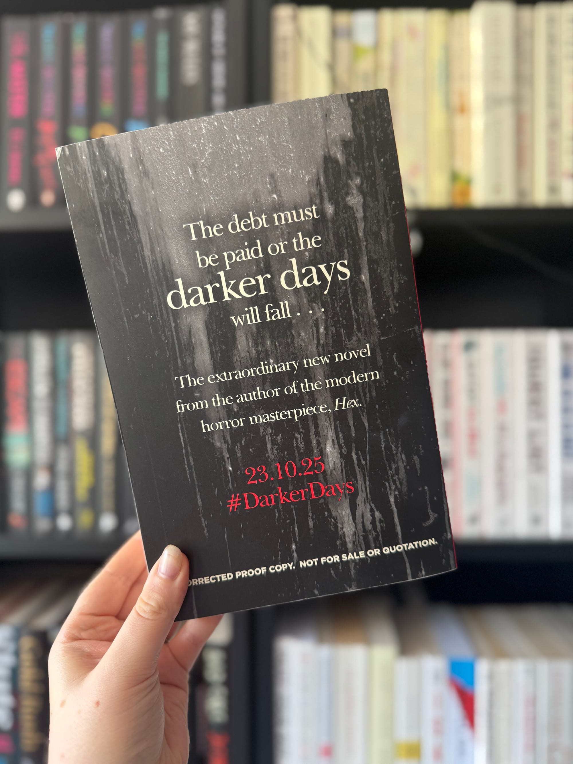 Hand holding a book titled "Darker Days" against a bookshelf. Text mentions, "The debt must be paid or the darker days will fall." Mood: suspenseful.