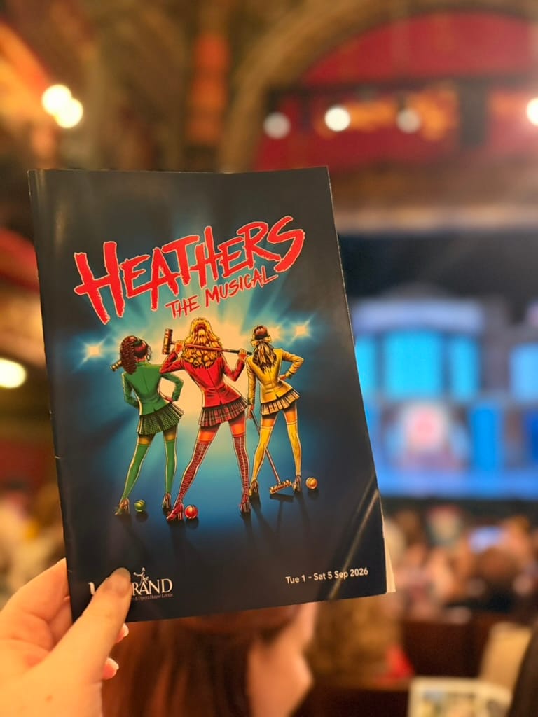 The cast of Heathers the Musical taking their bows on stage at Leeds Grand Theatre, including Veronica, JD and the three Heathers in their colourful costumes.