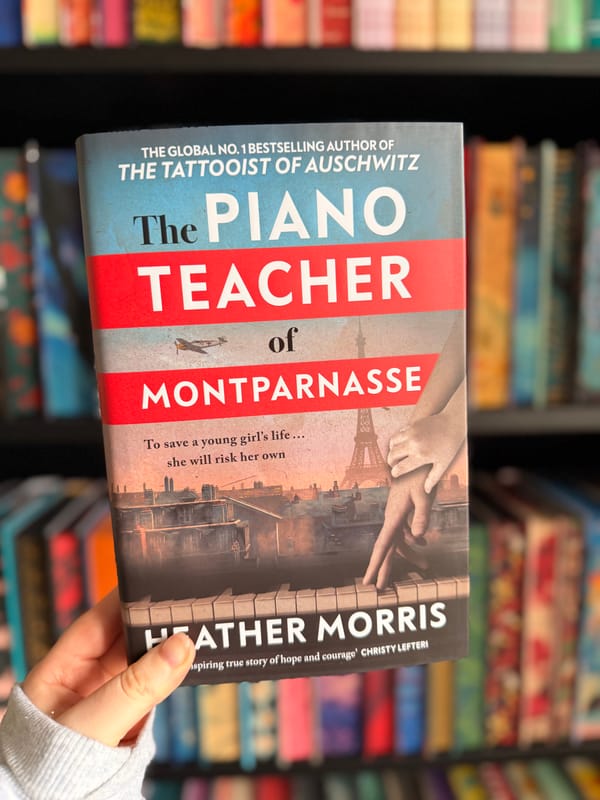 A hand holding a copy of The Piano Teacher of Montparnasse by Heather Morris.