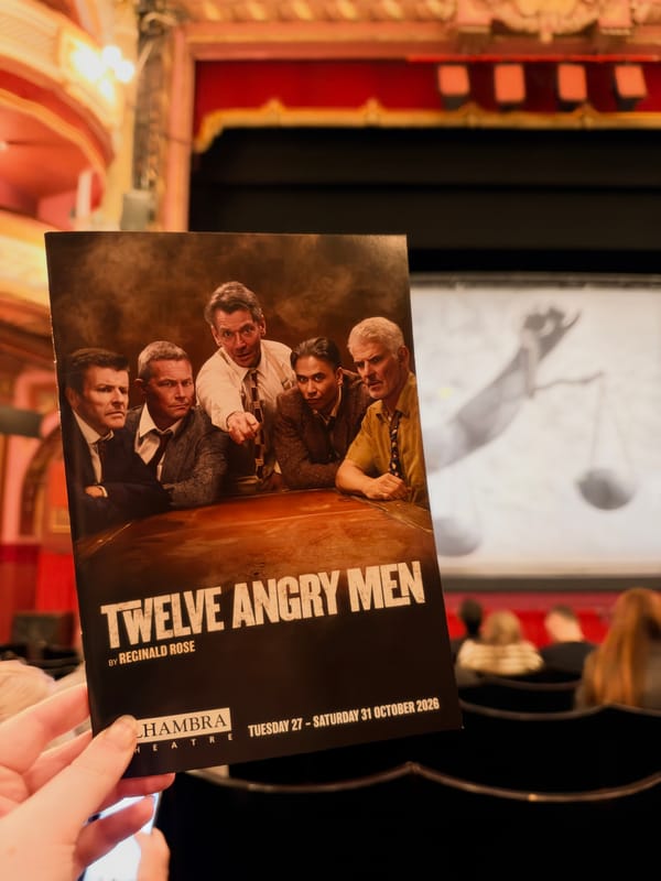 A hand holds a programme for Twelve Angry Men by Reginald Rose inside the Alhambra Theatre. 